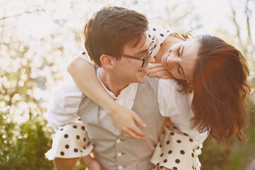 Man and woman in blooming garden on spring day. Couple in love spend time in spring garden. Flowers on background.