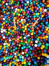 High Angle Portrait Of Happy Girl Lying Amidst Colorful Balls In Pool