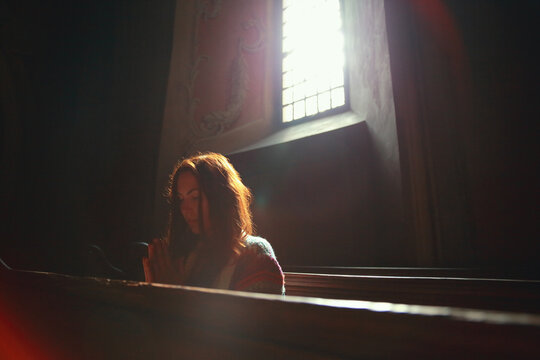 Young Caucasian woman prays in a church. 