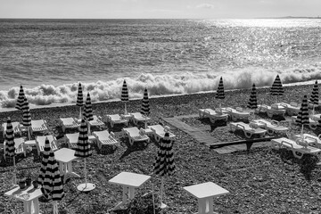 Wall Mural - Nice, France, October 14, 2019. Picturesque waves in the Mediterranean Sea. Cafe tables on a beach 