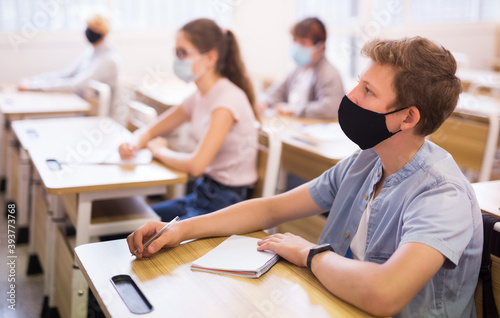 Fotografía Portrait of diligent schoolboy wearing protective face mask sitting in class wor