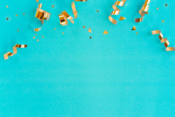 Wall Mural - close up on group of gold color of rolling ribbon and confetti on teal background with copy space fo