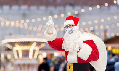 Poster - winter holidays and health concept - man in costume of santa claus with bag wearing face medical mask over christmas market in tallinn city