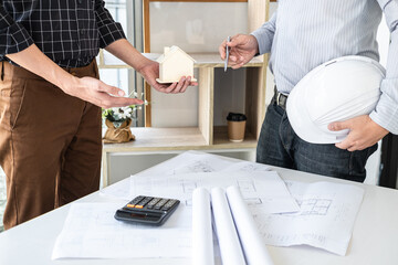 Wall Mural - Construction engineering or architect discussing a blueprint and building model while checking information on sketching meeting for architectural project in work site