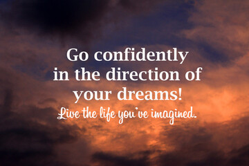 Inspirational motivational quote - Go confidently in the direction of your dreams. Live the life you have imagined. Positive message on blurry sunset sky clouds background.
