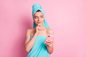 Wall Mural - Portrait of nice cute young lady hold telephone look empty space finger chin wear teal bath clothes isolated on pastel pink color background