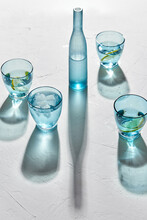 Drink, Detox And Diet Concept - Blue Glasses With Water, Lemons And Ice On White Background