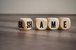 Cubes, blocks or dice with blame and shame on wooden background