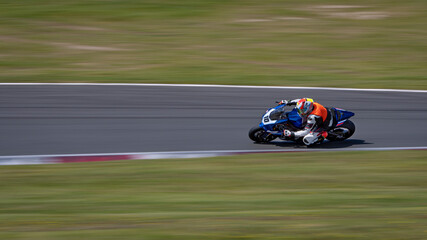 A panning shot of a racing bike cornering on a track.