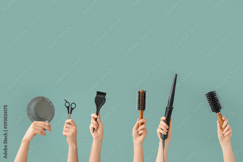 Female hands with hair tools on color background