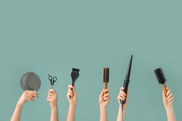 Female hands with hair tools on color background