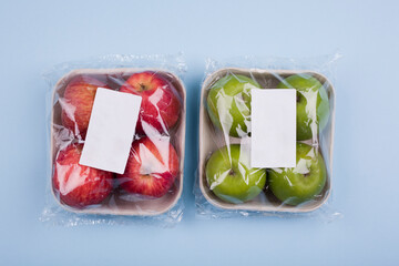 Wall Mural - Plasticized fresh red and green apples in pulp paper trays. Studio photo isolated on light blue background.