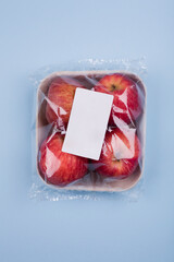 Wall Mural - Plasticized four fresh red apples in a pulp paper tray. Studio photo isolated on light blue background.