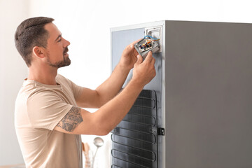 Poster - Worker repairing fridge in kitchen