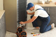 © Pixel-Shot - Worker repairing fridge in kitchen