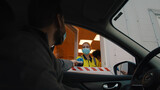 Fototapeta Kuchnia - Man driver in mask showing pass card to worker in booth before entrance in pass control area