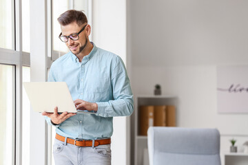 Wall Mural - Portrait of male psychologist with laptop near window in office