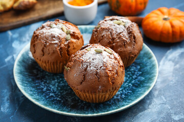 Plate with tasty pumpkin muffins on color background