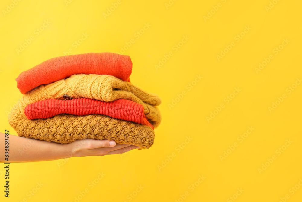 Female hands with warm clothes on color background