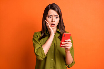 Wall Mural - photo of frightened young girl hold cellphone arm cheekbone look screen wear green shirt isolated or