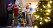 © VAKSMANV - Joyful Caucasian family with kids gathered together at cozy home decorating xmas tree with twinkle lights chatting and smiling on Christmas Eve in evening. New Year concept. Winter holiday