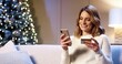 © VAKSMANV - Close up portrait of happy positive Caucasian beautiful woman buying on internet xmas presents paying with credit card using cellphone at cozy decorated home. Xmas sale and discounts. Holiday shopping