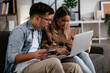 © JustLife - Young couple using credit card and laptop at home. Boyfriend and girlfriend buying online..