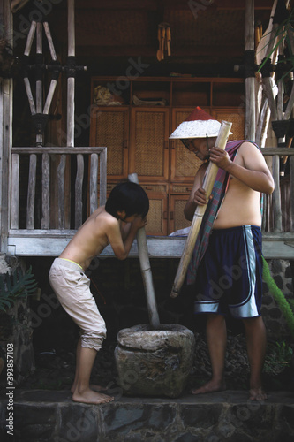 Plakat Two asian farmers pound using traditional mashing tools. Traditional activity in village concept.