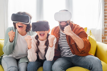 Wall Mural - excited hispanic family showing winner gesture while using vr headsets