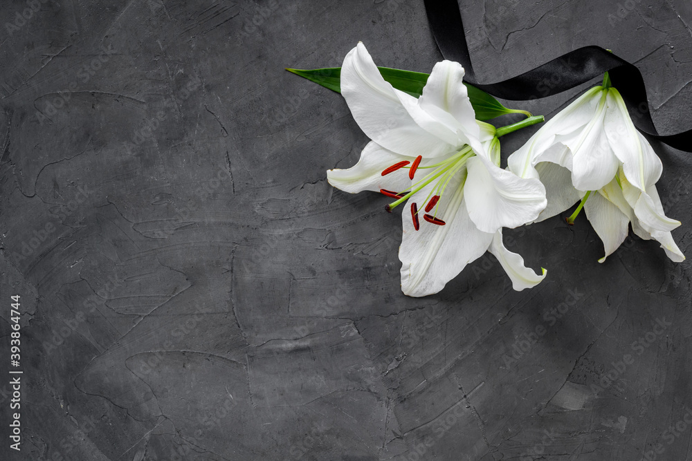 Lily funeral flower on dark stone. Condolence card with copy space - obrazy, fototapety, plakaty 