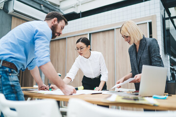 Wall Mural - Group of working colleagues standing around table in office