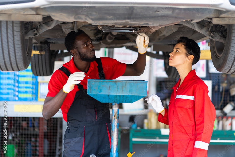 Black Male And Female trainee Mechanics Working Underneath Car Together ...