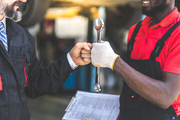 Auto mechanic with wrench in hand. stranglehold. Closeup car repair black man hand and caucasian man customer.