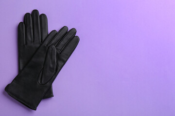 Poster - Pair of stylish leather gloves on violet background, flat lay. Space for text