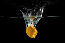 Close Up View Of Yellow Pepper Vegetable Falling Into Water Isolated On Black Background