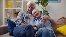 Smiling Woman With Cancer Hugging Husband Sitting On Couch At Home