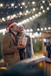 A young happy couple in love watching snowfall at christmas festival in the city. Festival, love, relationship, Xmas, snow