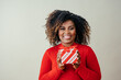 © Carlos David - Portrait of a very happy mid woman smiling and holding red Christmas gift box