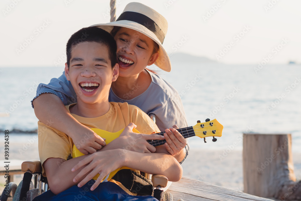 Asian special child on wheelchair is singing, playing ukulele happily ...