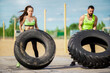© Georgii - Powerful exercising of young athletic couple outside. Young girl and guy lifting tyres outside.