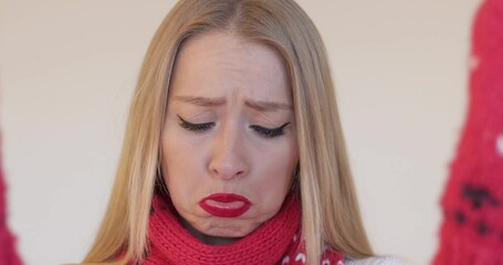 Wall Mural - Stock video of happy, sad, angry blonde Caucasian woman with makeup looking at camera through red winter mittens at Christmas.