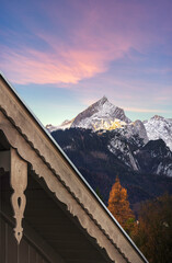 Wall Mural - beautiful view of first sunlight on alpsitze mountain with artistic wooden roof in foreground