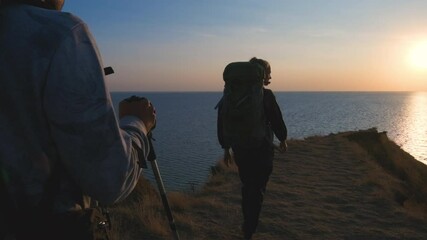 Wall Mural - the man and woman with backpacks walking on mountain near the sea. slow motion