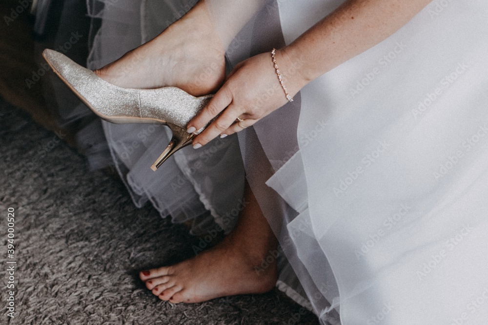 Kobieta panna młoda w dniu ślubu zakłada buty szpilki na obcasie na stopy - obrazy, fototapety, plakaty 