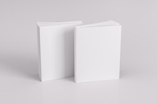Two Softcover Or Paperback Vertical White Mockup Books Standing On The White Table. Blank Front And Back Cover