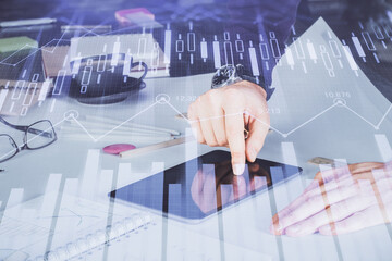 Double exposure of man's hands holding and using a digital device and forex graph drawing. Financial market concept.