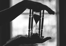 Silhouette Hand Holding Hourglass Indoors