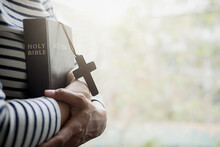 Close-up Of Woman With Wooden Cross And Bible At Home