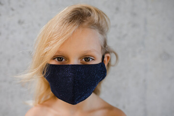 Little blond girl in sparkling face mask 