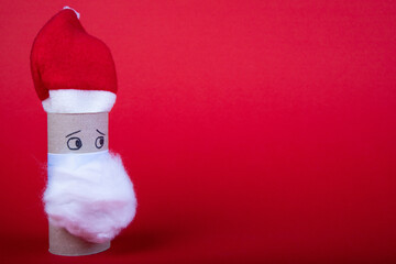 empty toilet roll with a sad face, red cap and beard, as a Santa Clause on a red background